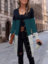 a woman standing on a cobblestone street wearing a green and black cardigan