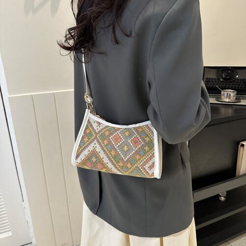 a woman wearing a gray jacket holding a white purse