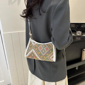 a woman wearing a gray jacket holding a white purse
