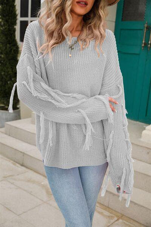 a woman wearing a gray sweater and jeans