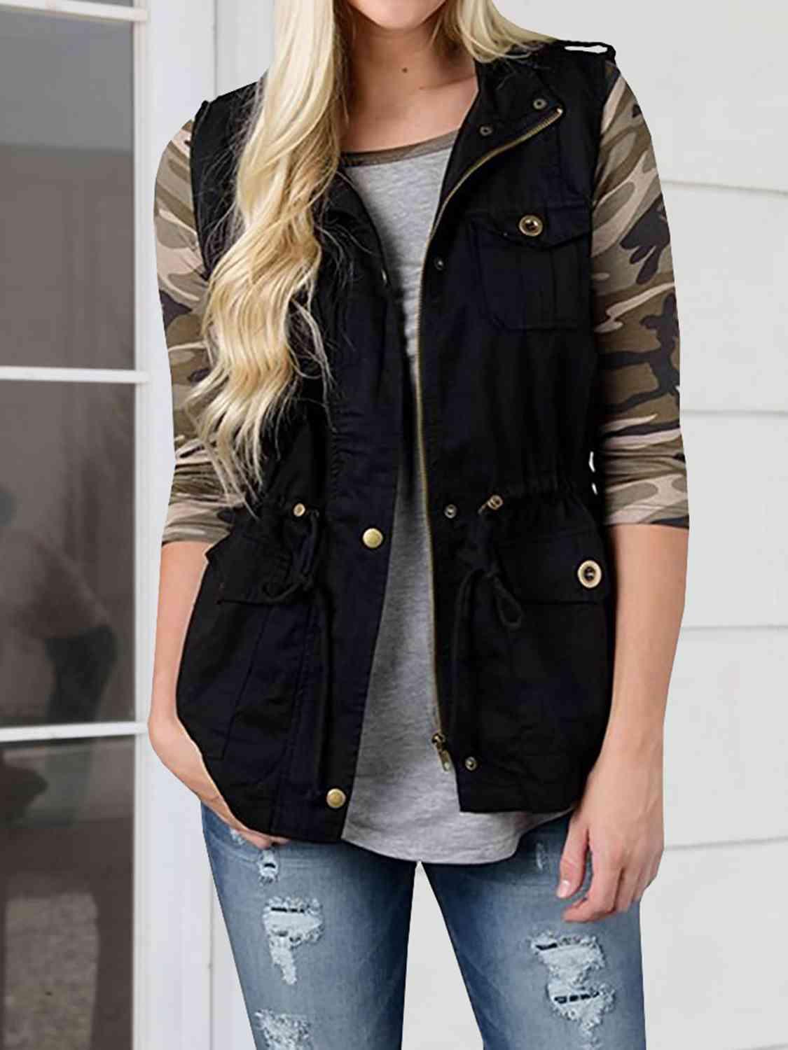 a woman wearing a black vest and jeans