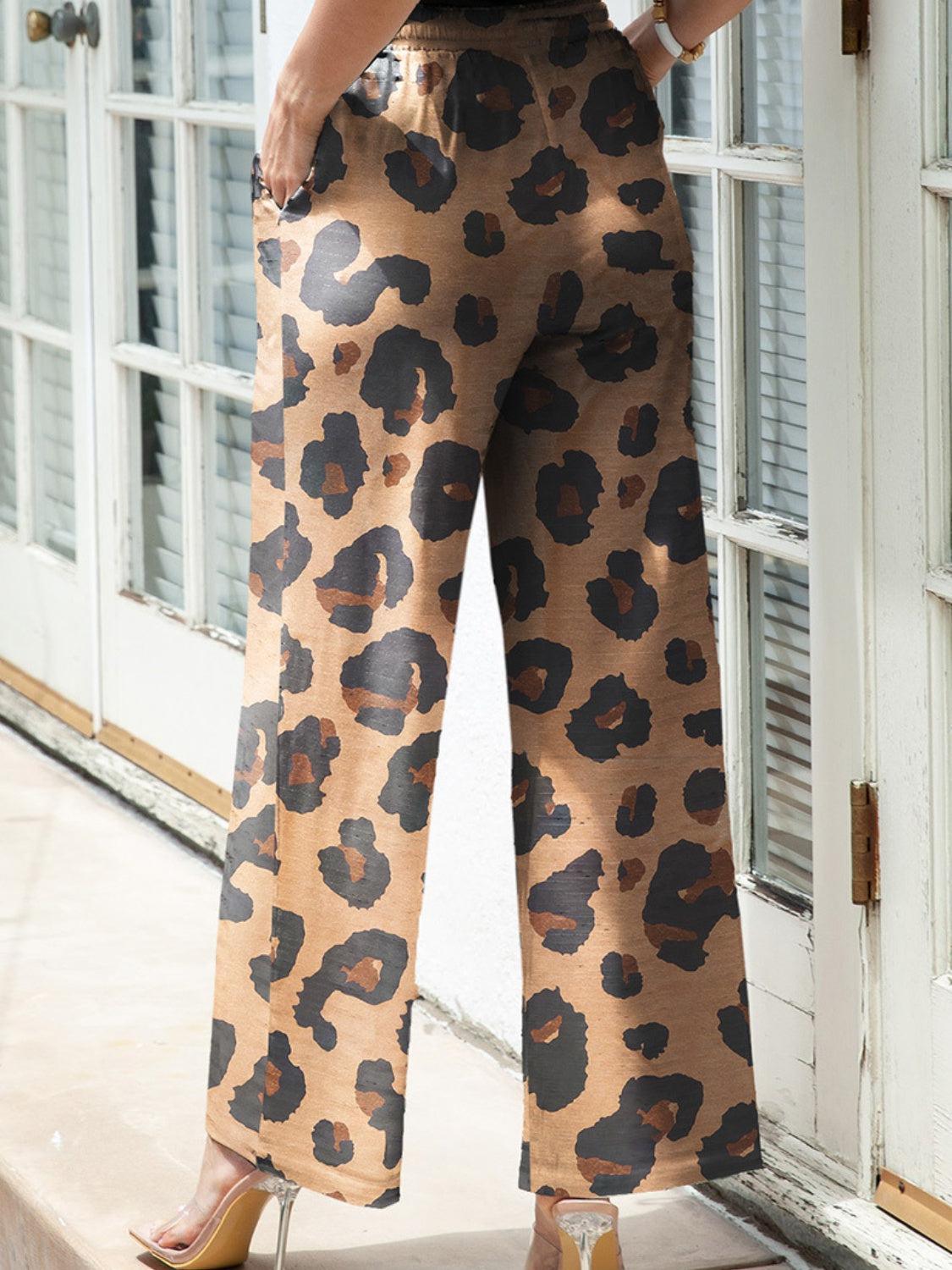 a woman standing in front of a door wearing leopard print pants