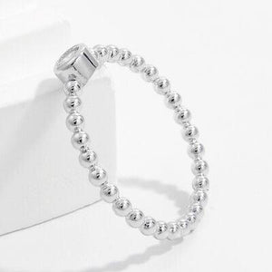 a silver beaded ring sitting on top of a white box