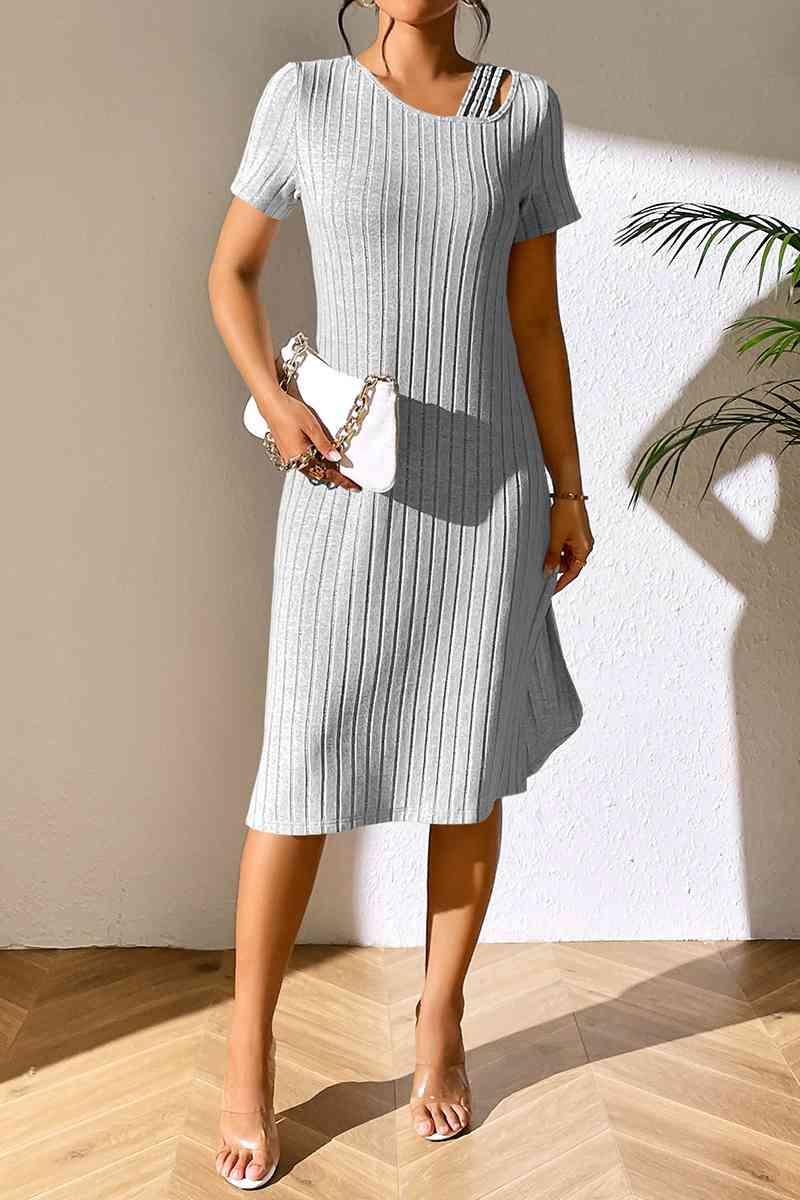 a woman standing in a room wearing a gray dress