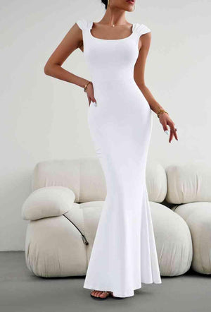 a woman in a white dress standing in front of a couch