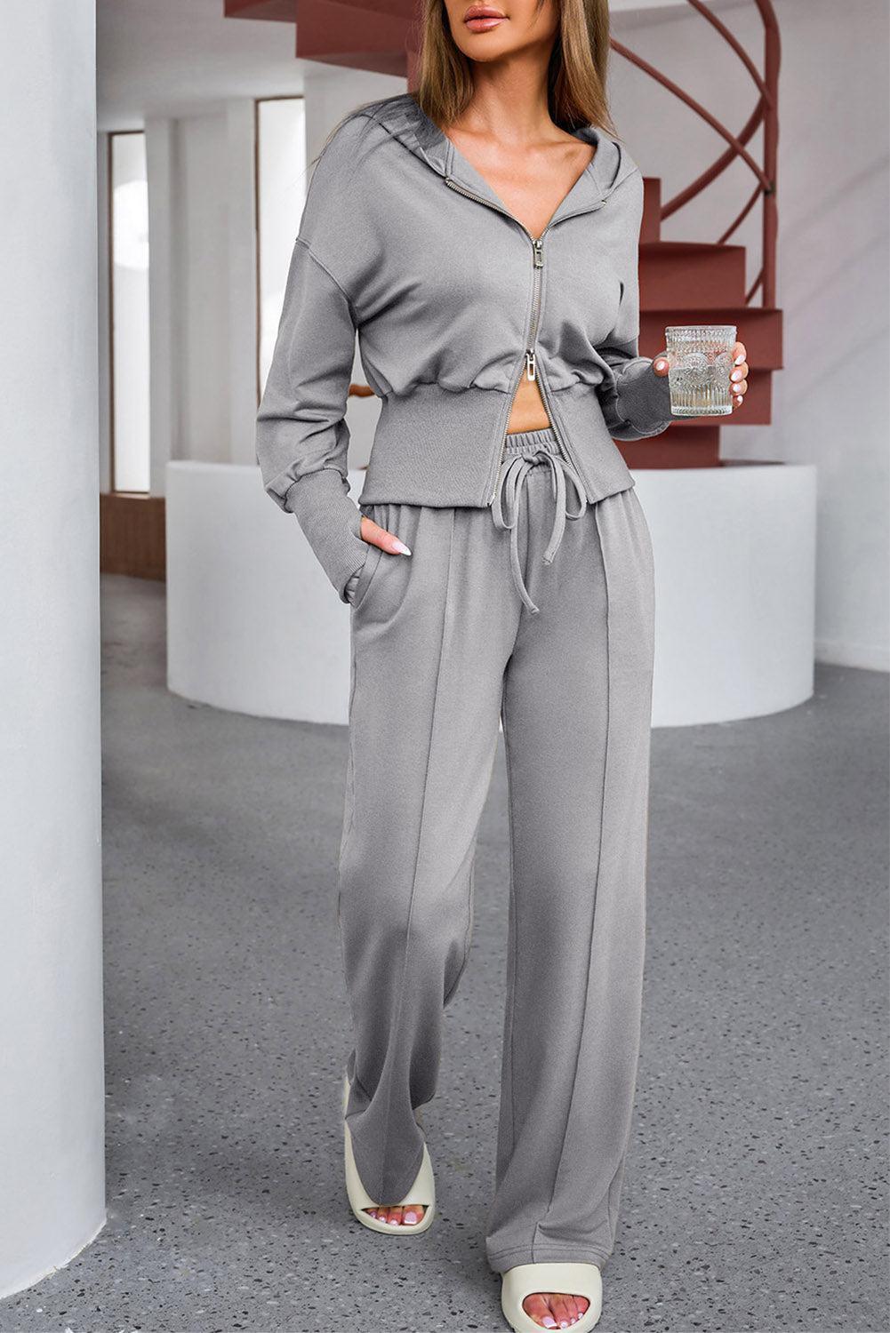 a woman standing in a room wearing a gray outfit