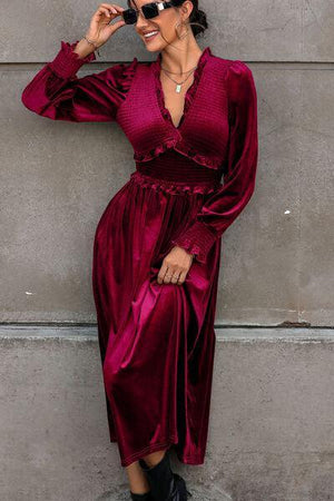 a woman in a red dress leaning against a wall
