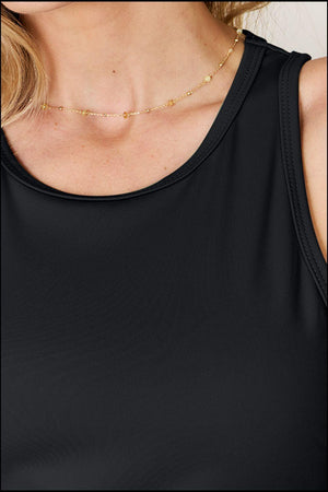 a woman wearing a black top and a gold necklace