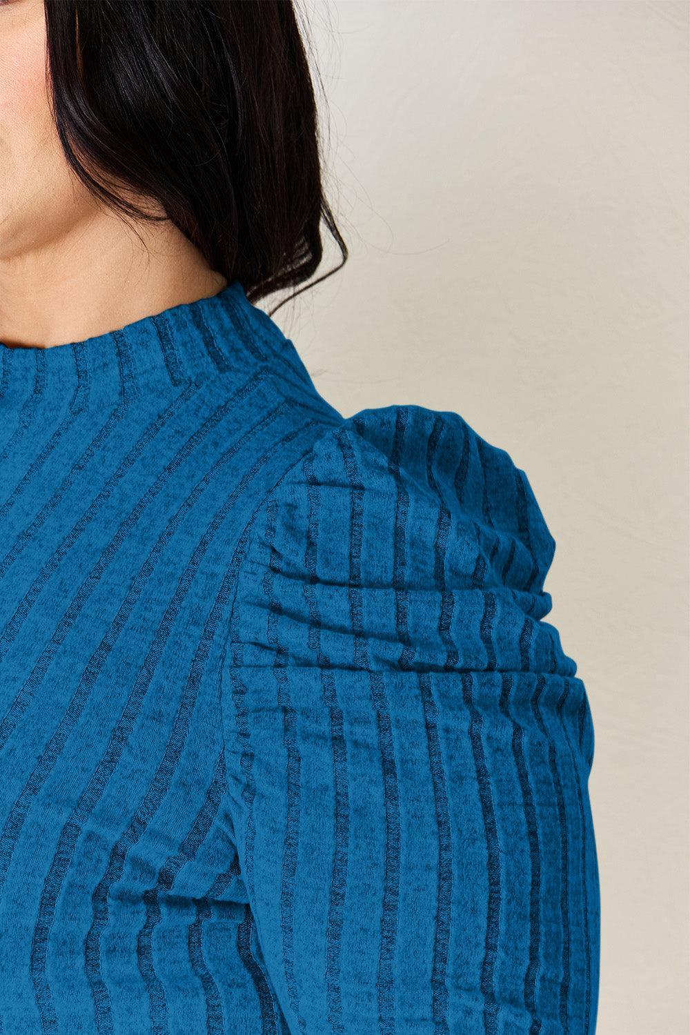 a woman wearing a blue top with a tie around her neck