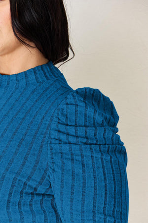 a woman wearing a blue top with a tie around her neck