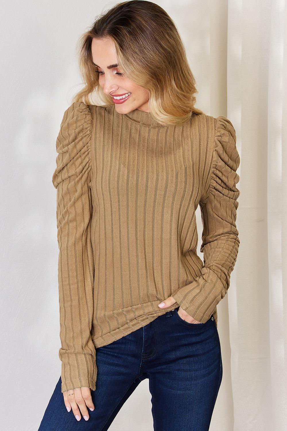 a woman wearing a tan sweater and jeans