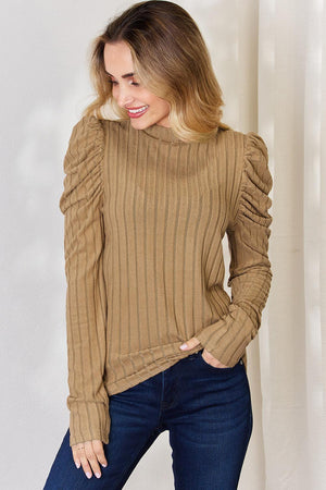a woman wearing a tan sweater and jeans