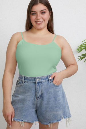 a woman wearing a green tank top and denim shorts