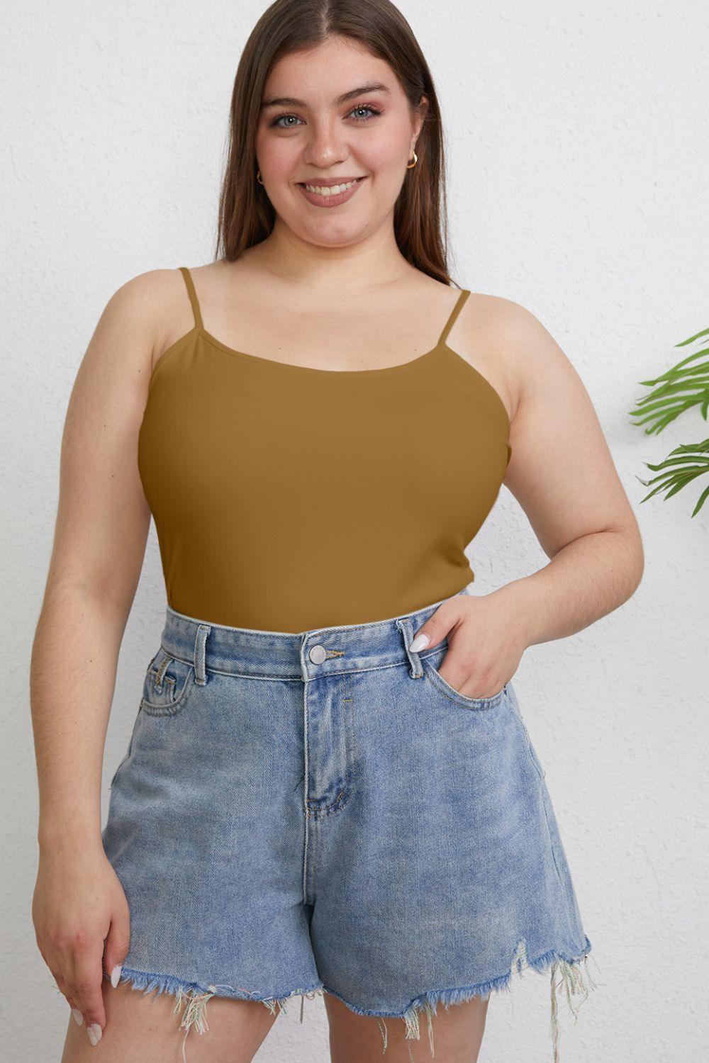 a woman wearing a tan top and denim shorts