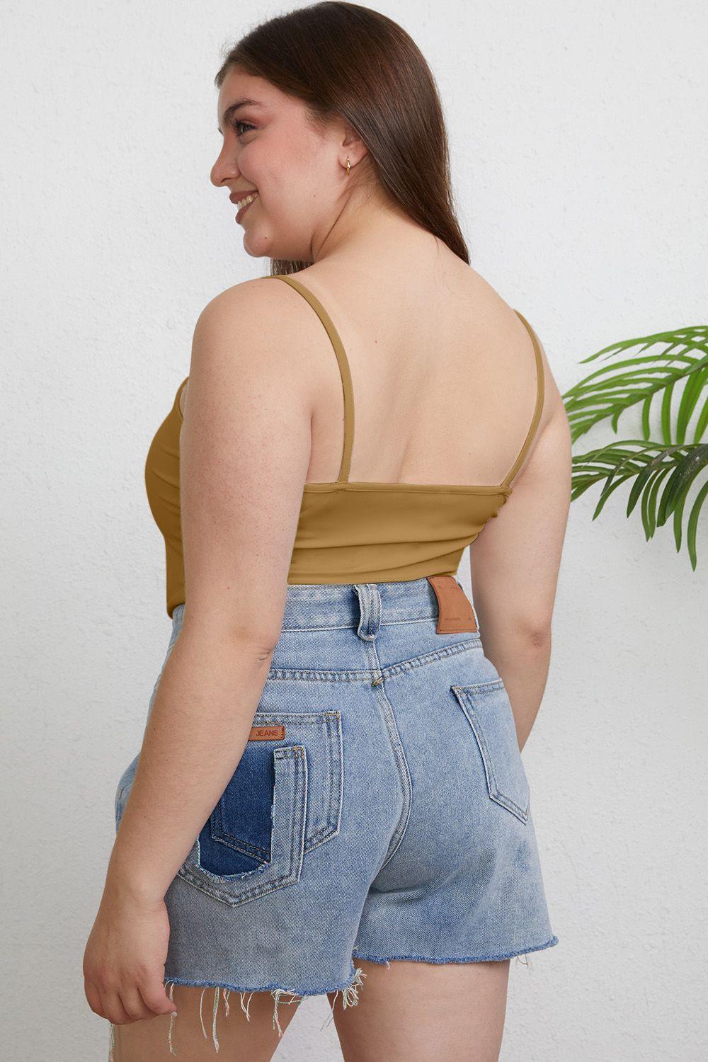 a woman wearing a tan top and denim shorts