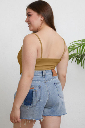 a woman wearing a tan top and denim shorts