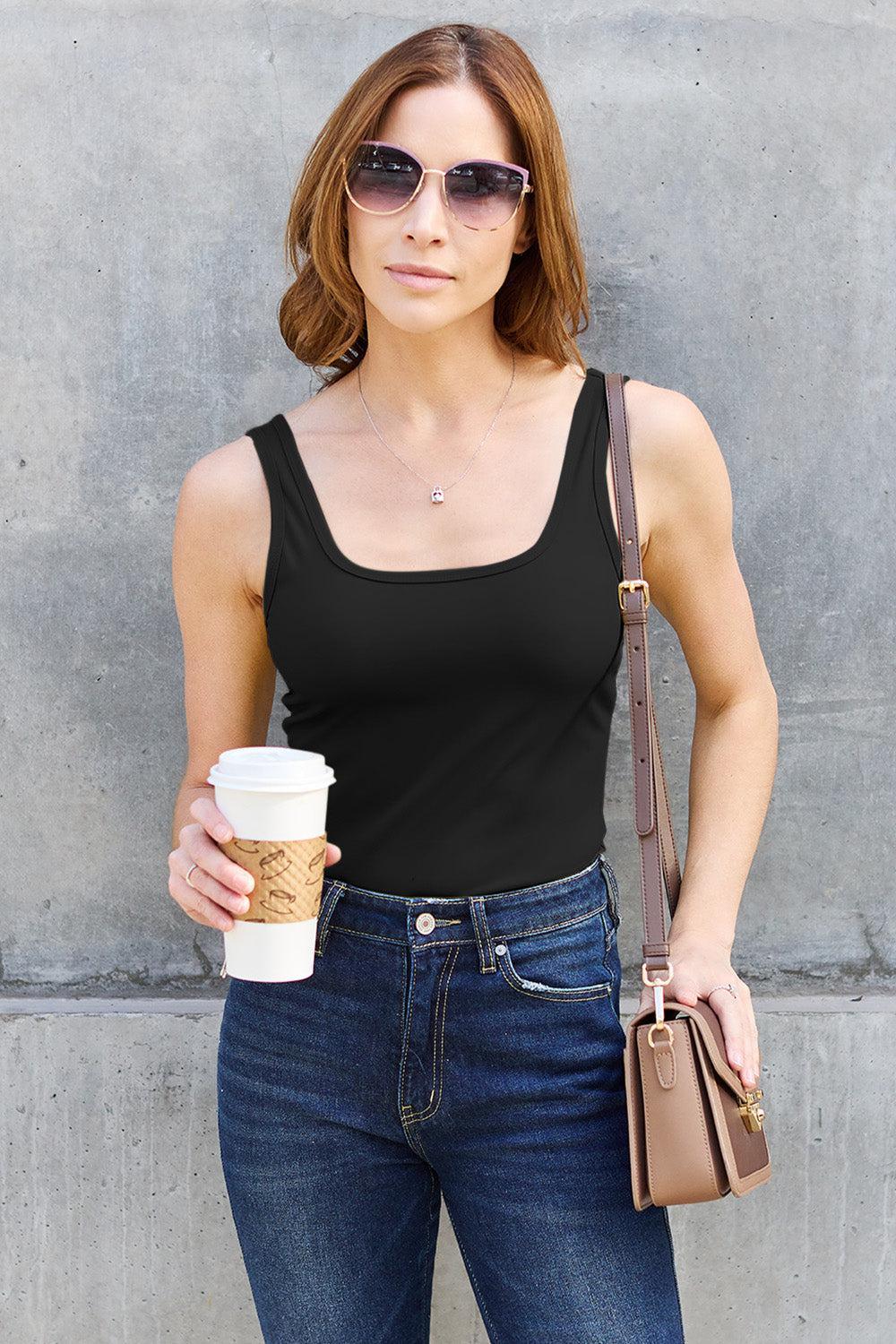 a woman holding a cup of coffee and wearing sunglasses