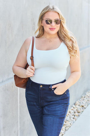 a woman wearing a white tank top and jeans