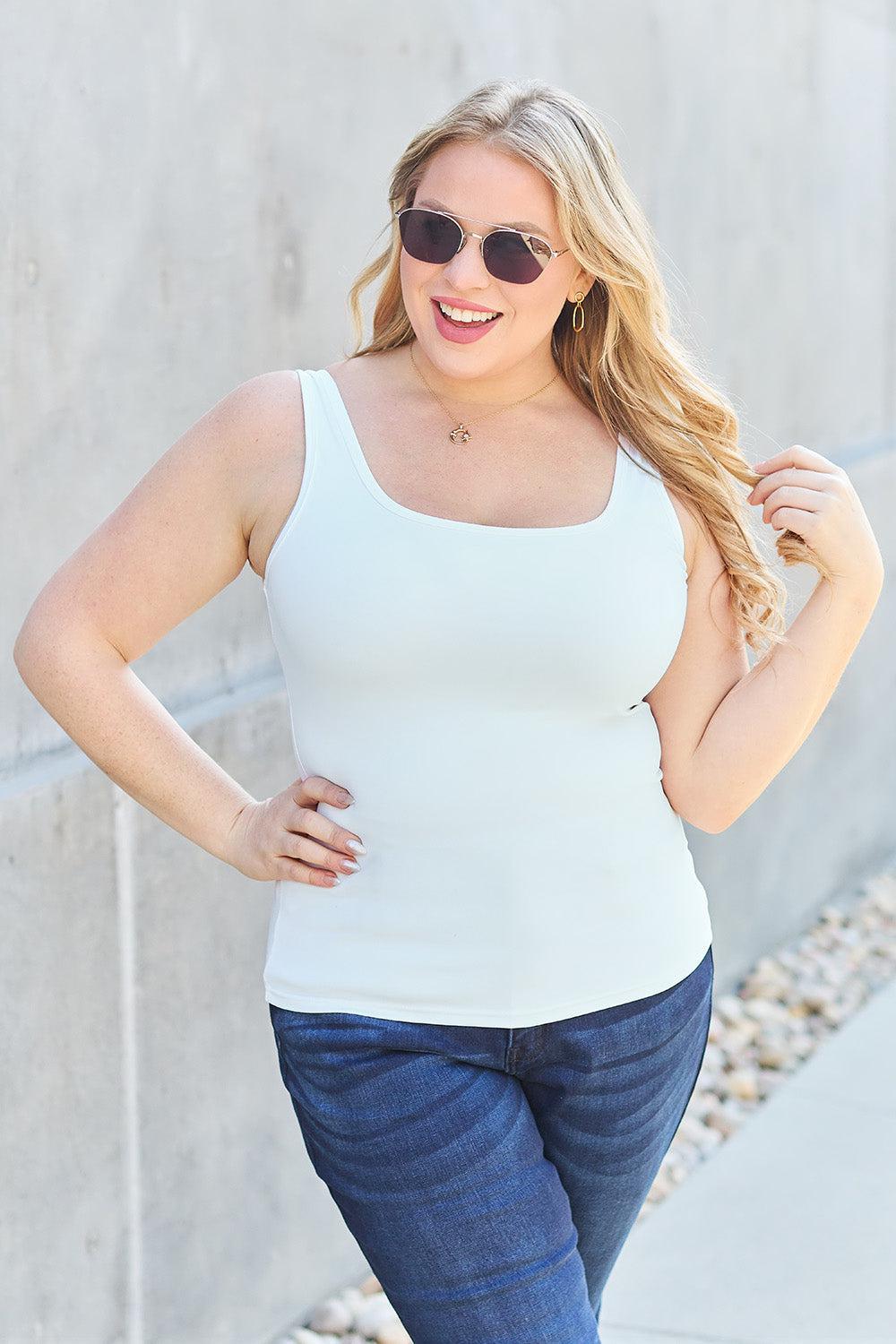 a woman wearing a white tank top and jeans