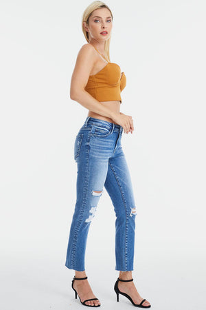 a woman in a tan top and ripped jeans