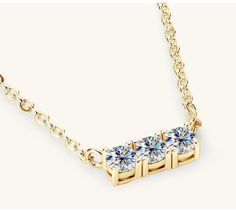 a gold necklace with three diamonds on it