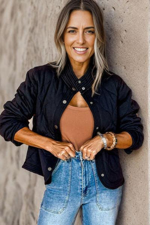 a woman leaning against a wall with her hands on her hips