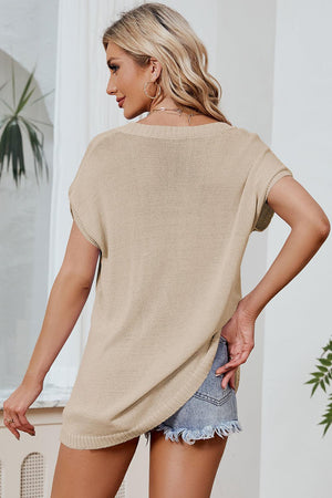 a woman wearing a tan sweater and denim shorts