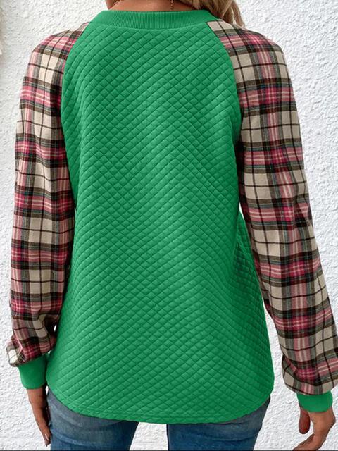 a woman wearing a green sweater and plaid shirt