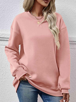 a woman wearing a pink sweatshirt and jeans