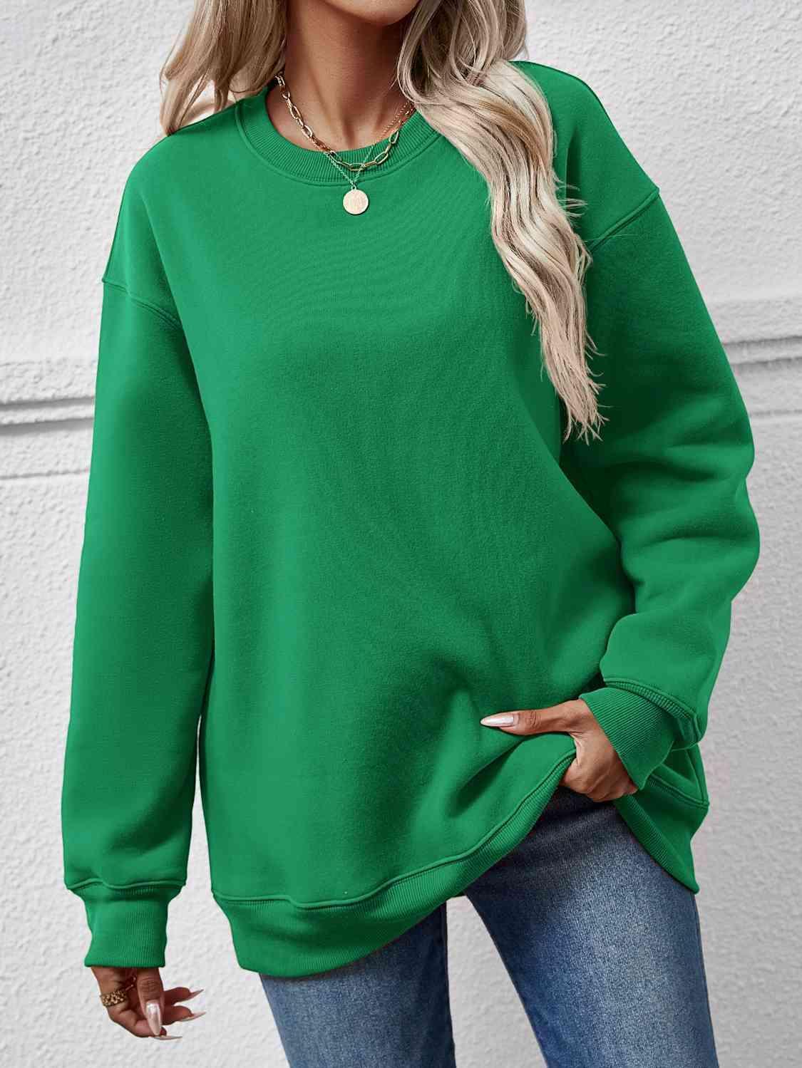 a woman wearing a green sweatshirt and jeans