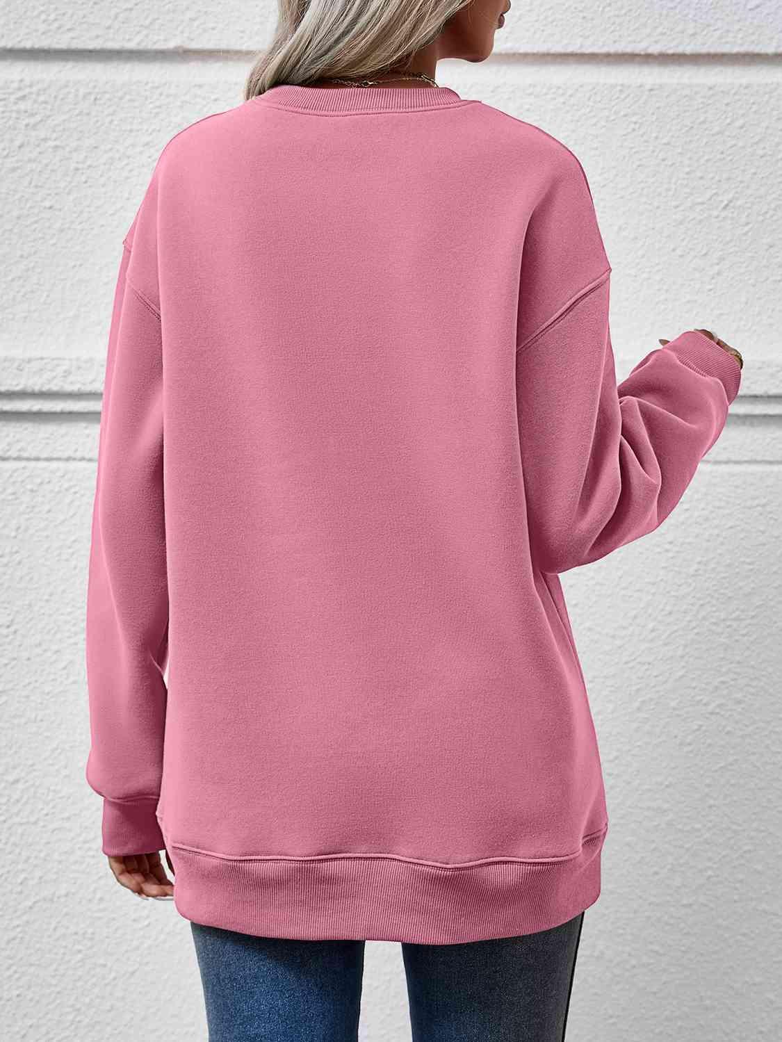 a woman wearing a pink sweatshirt and jeans