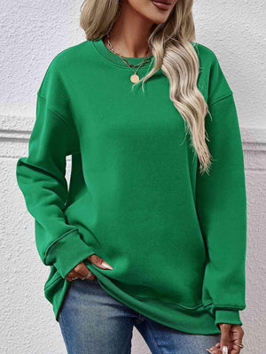 a woman wearing a green sweatshirt and jeans