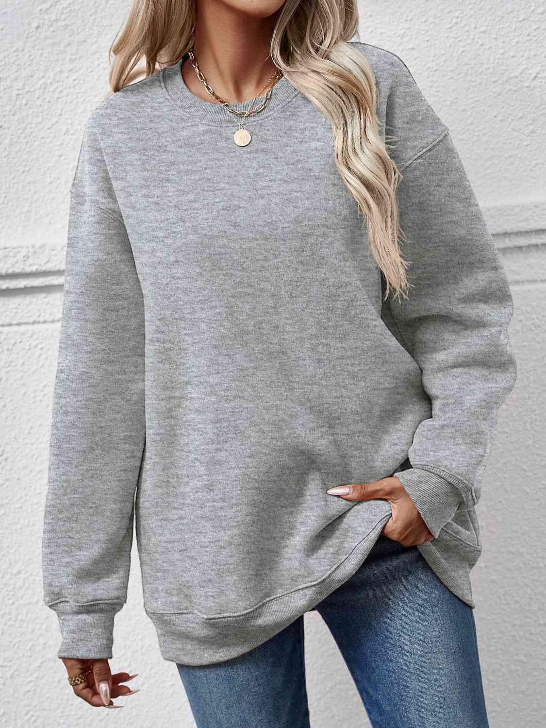 a woman wearing a grey sweatshirt and jeans