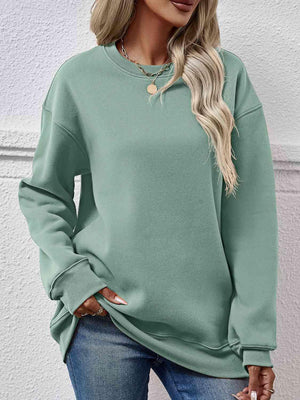a woman wearing a green sweatshirt and jeans