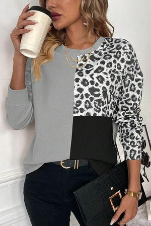 a woman holding a coffee cup and wearing a leopard print top