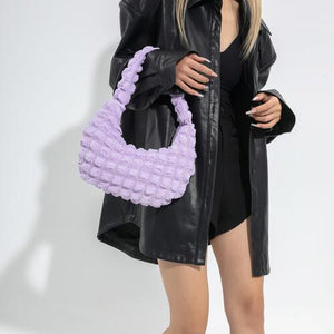 a woman in a black jacket holding a purple purse