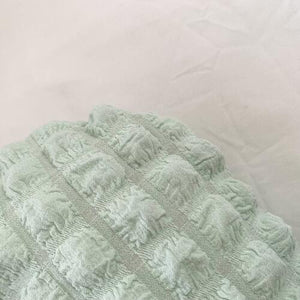 a white teddy bear laying on top of a green blanket