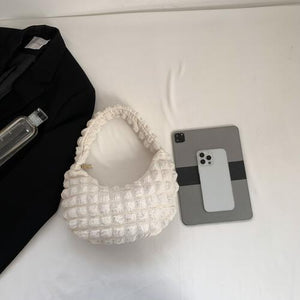 a white purse sitting next to a cell phone