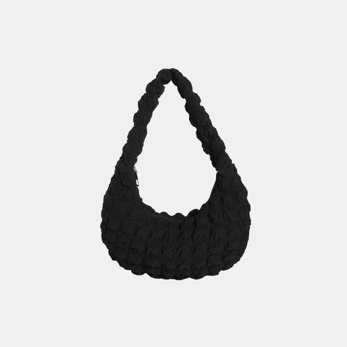 a black handbag hanging on a white wall