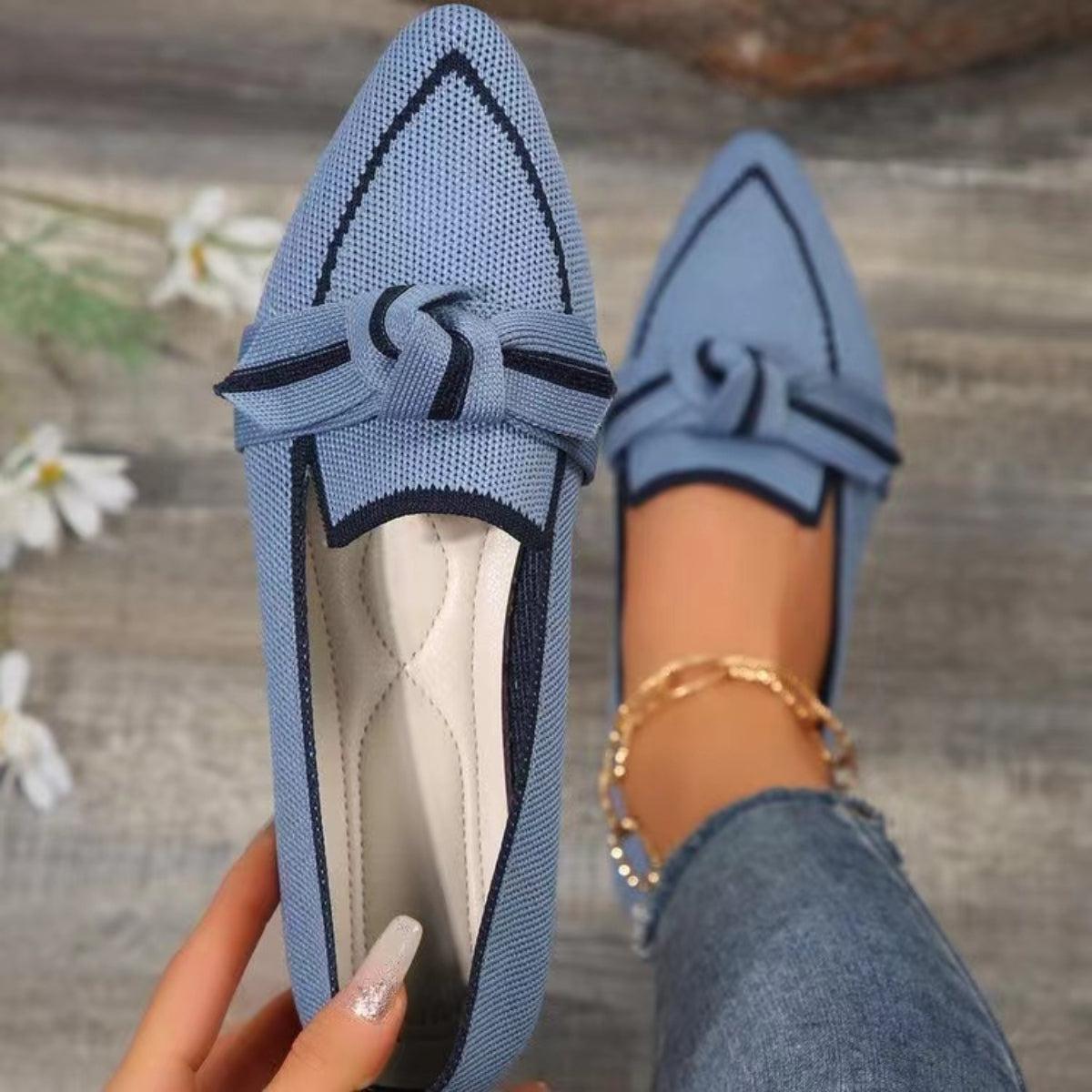 a woman's hand holding onto a pair of blue shoes