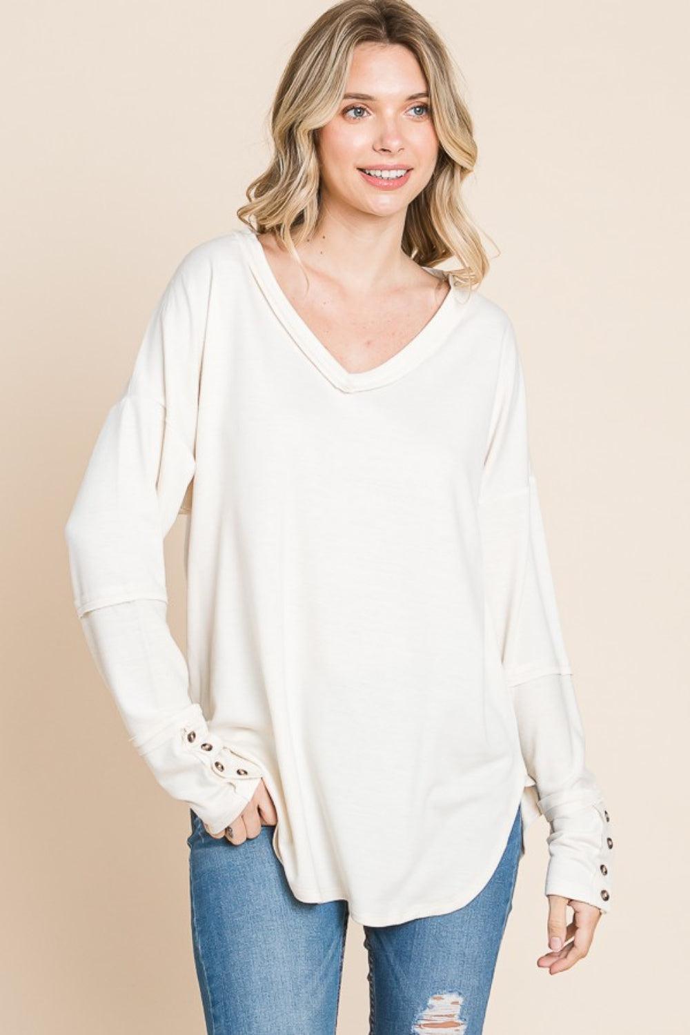 a woman wearing a white sweater and ripped jeans