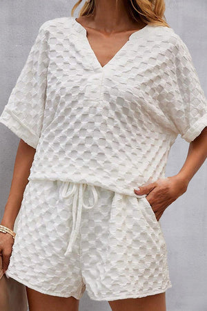 a woman wearing a white top and shorts