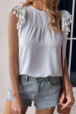 a woman wearing a white blouse and denim shorts