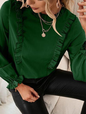 a woman wearing a green blouse and black pants