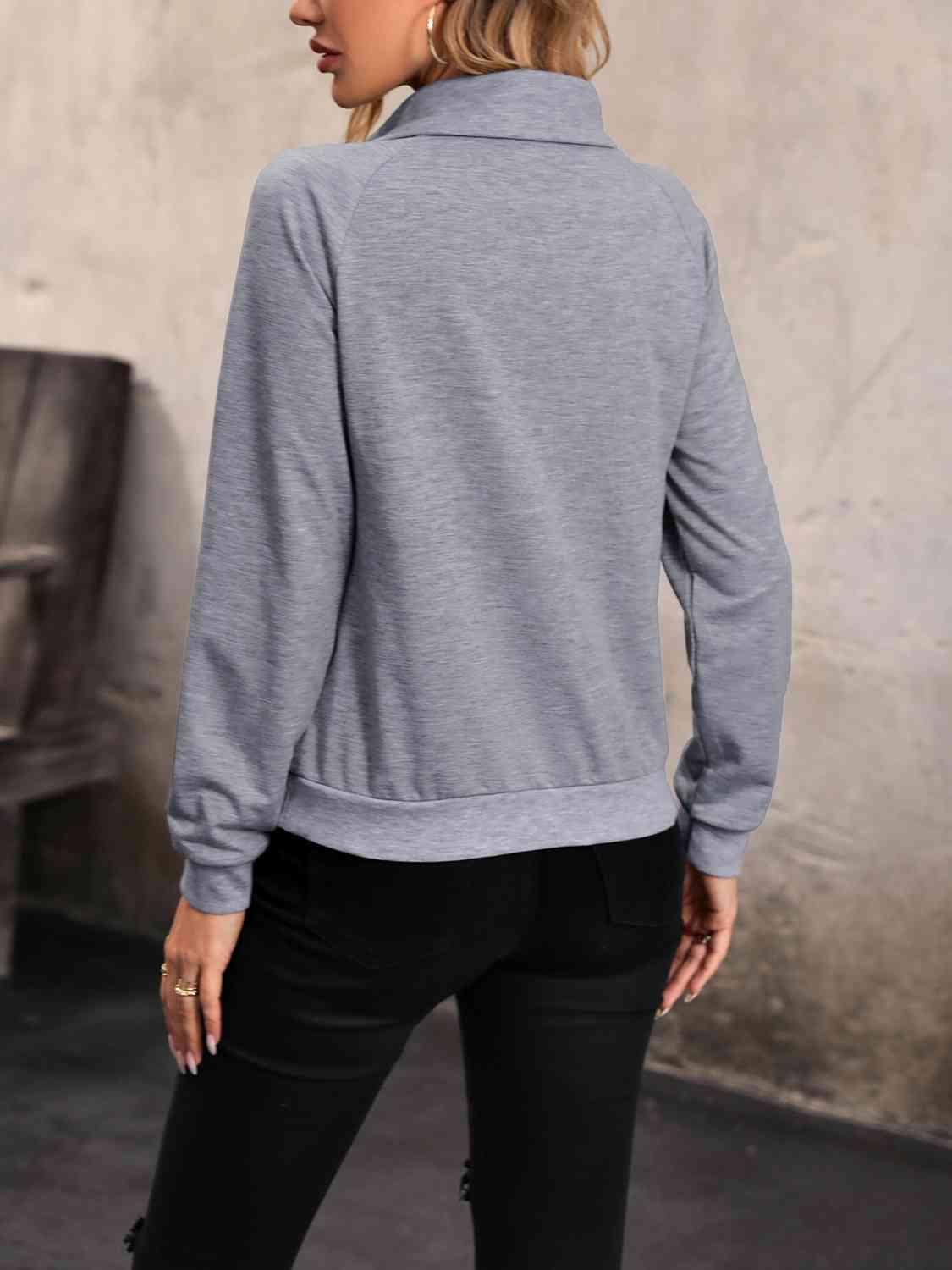 a woman wearing a grey sweater and black jeans