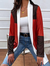 a woman sitting on a chair wearing jeans and a cardigan