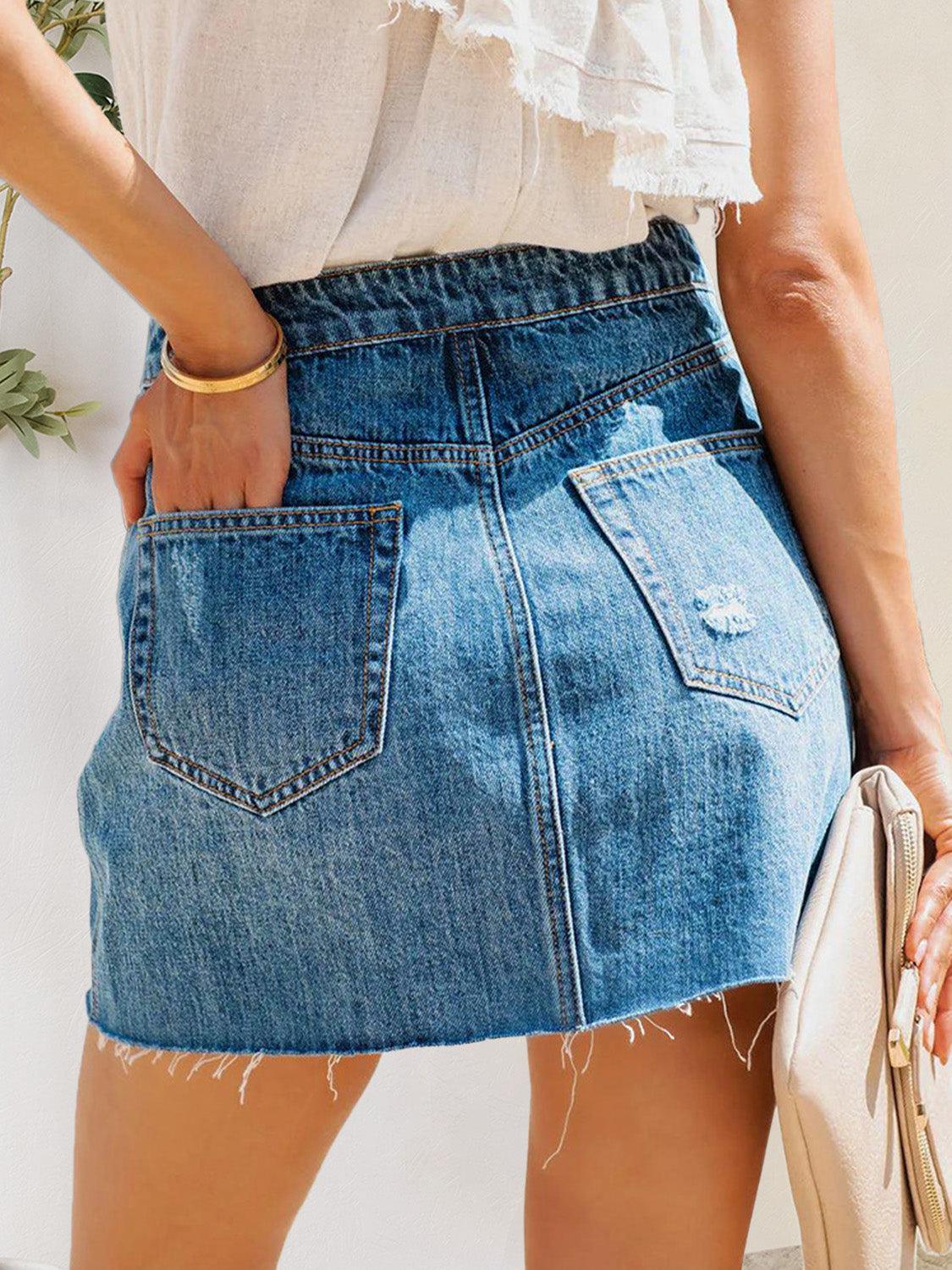 a woman wearing a denim skirt and a white top