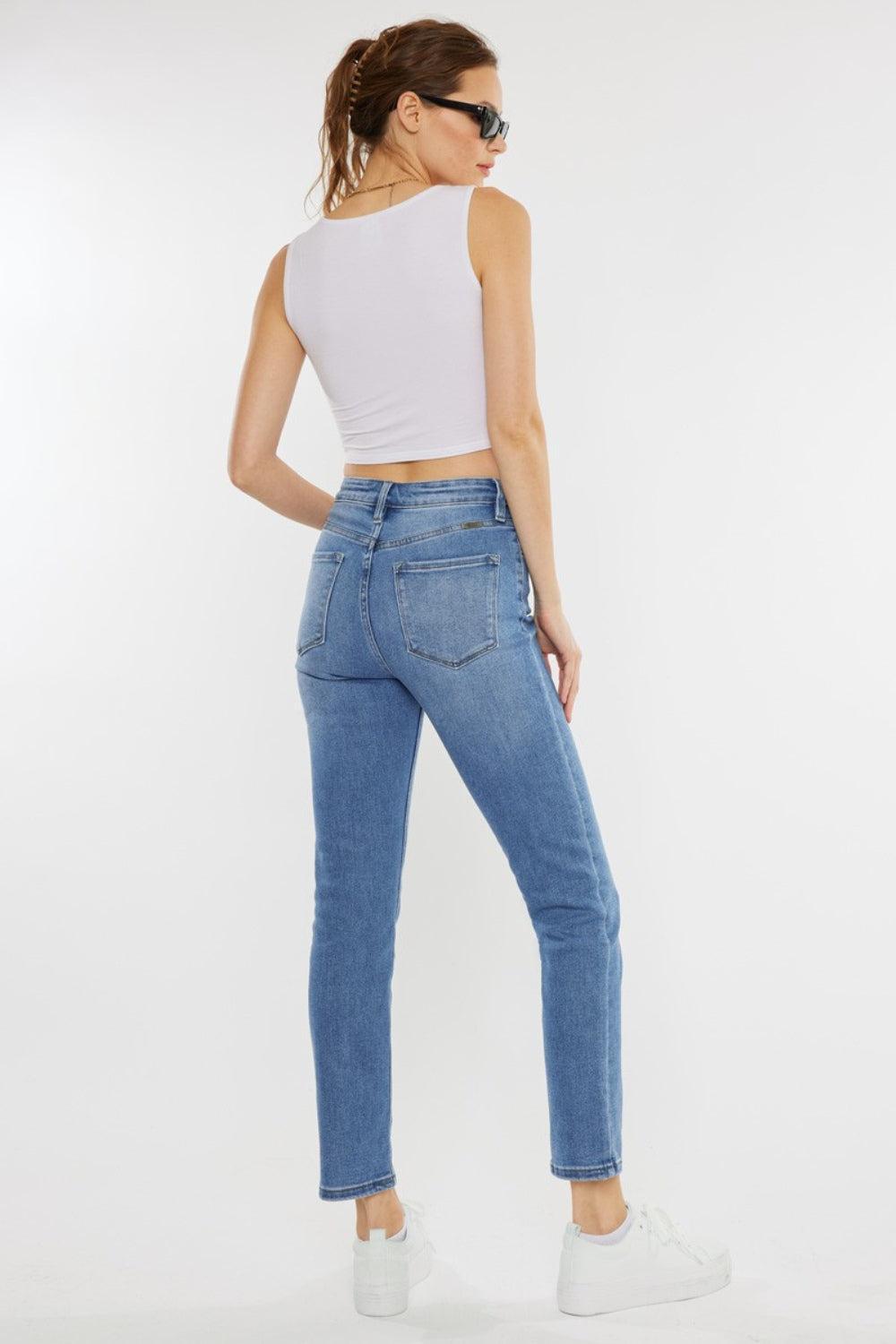 a woman wearing a white tank top and jeans