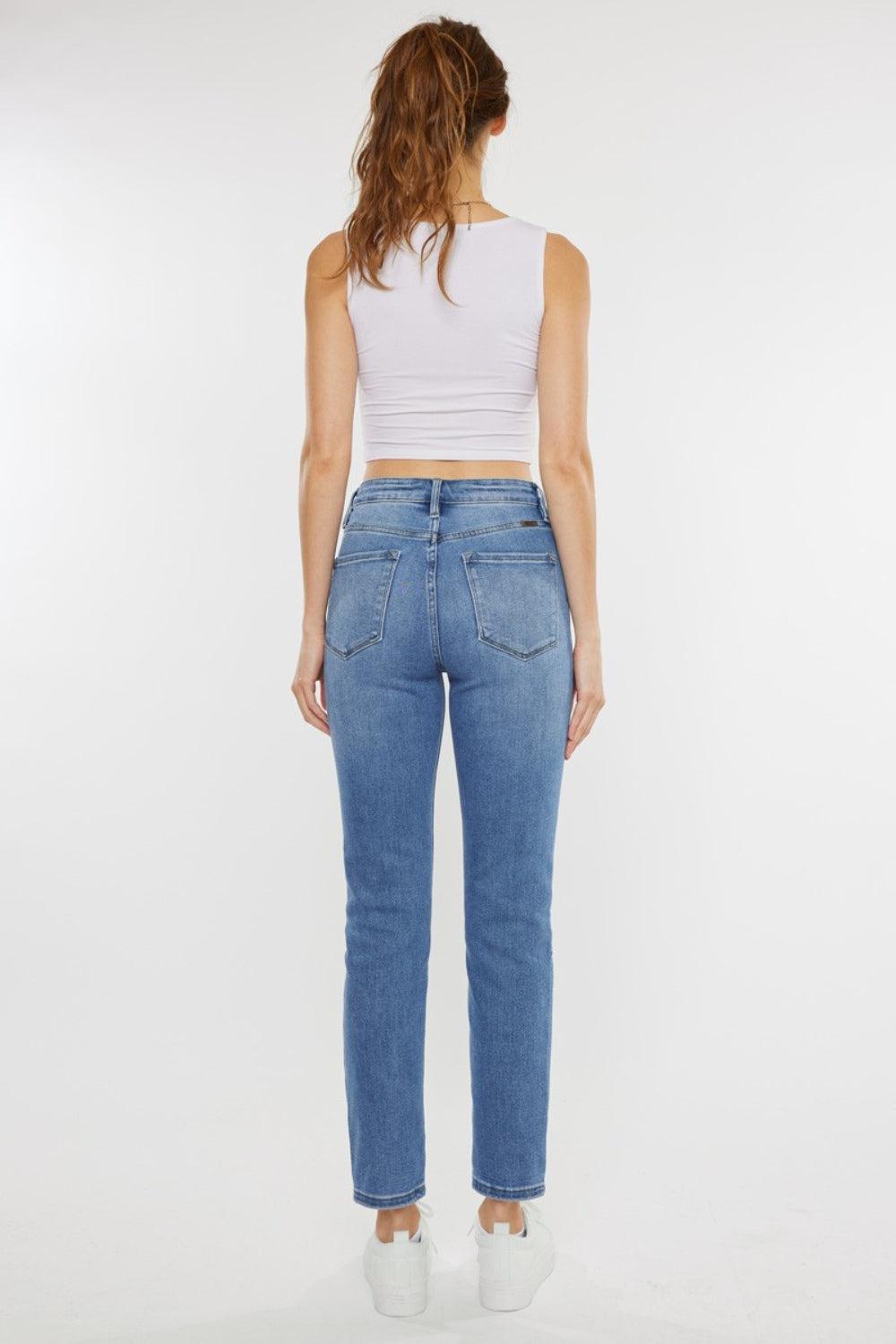 a woman in a white tank top and jeans