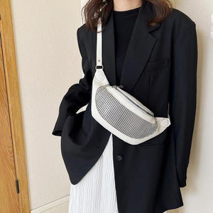 a woman wearing a black blazer and a white fanny bag